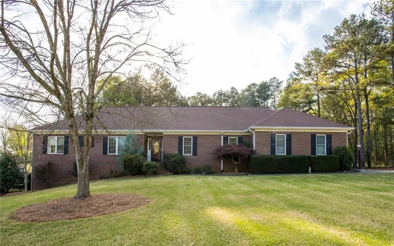 Brick exterior with contrasting dark shutters, a front entry door with sidelights, and a sloped front lawn