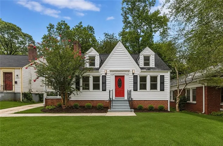 Gabled gray siding exterior with a red front door, featuring black shutters and a brick foundation