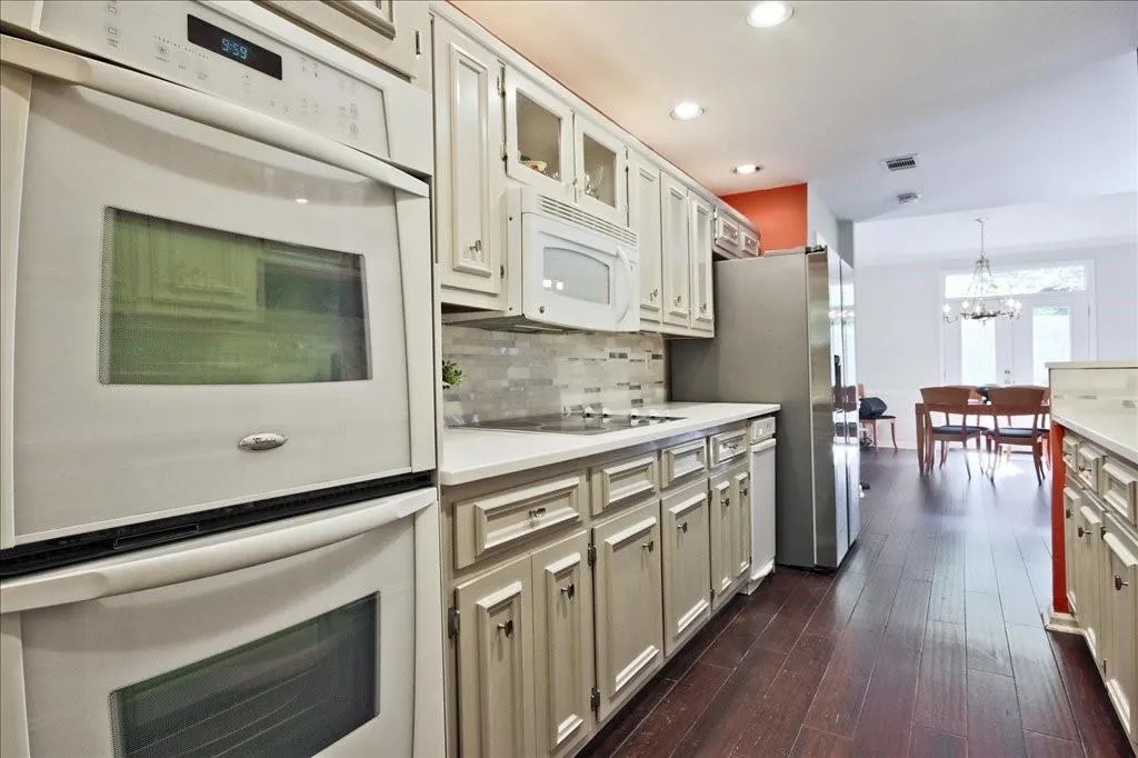 Kitchen with dark hardwood / wood-style flooring, a chandelier, tasteful backsplash, black electric cooktop, and double wall oven