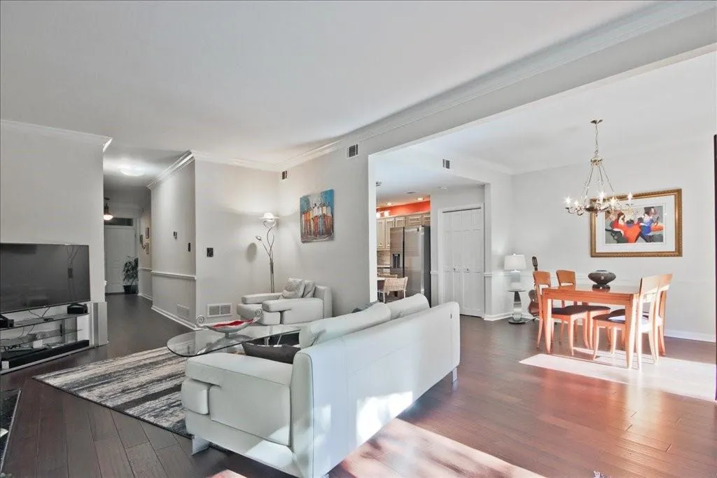 Living room featuring dark wood-type flooring, a chandelier, and crown molding