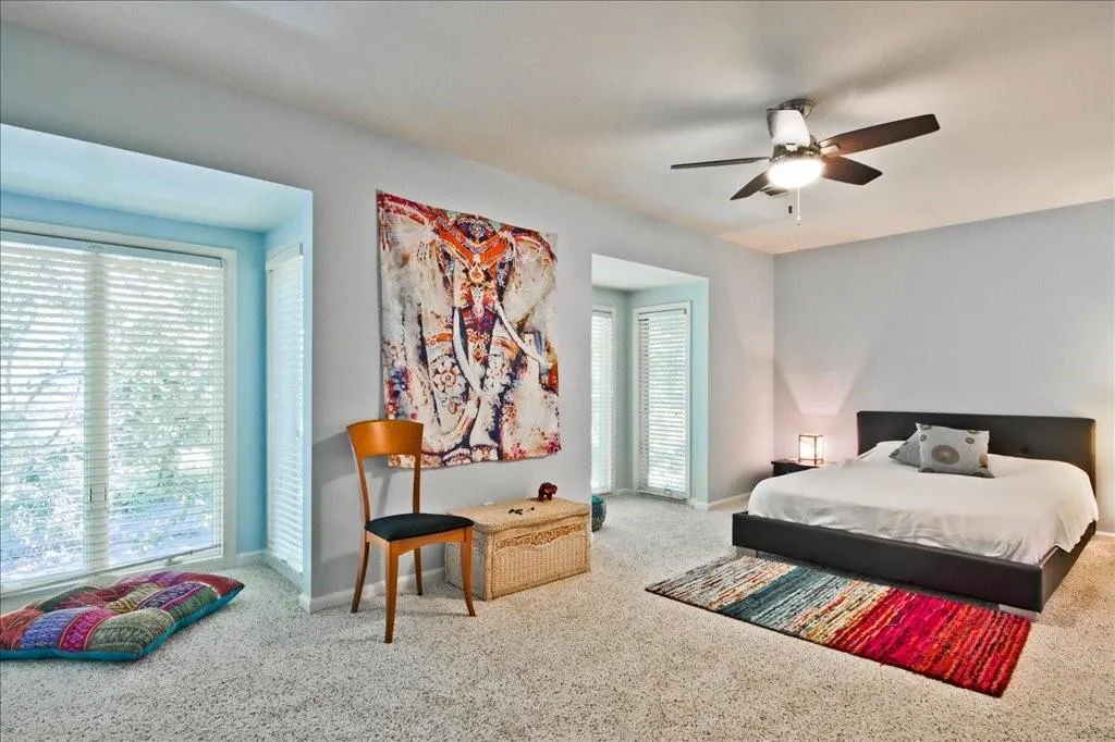 Bedroom featuring carpet, multiple windows, and ceiling fan