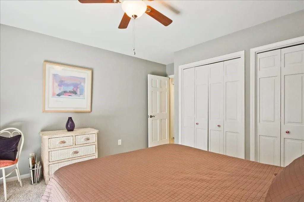 Bedroom featuring carpet flooring, ceiling fan, and multiple closets