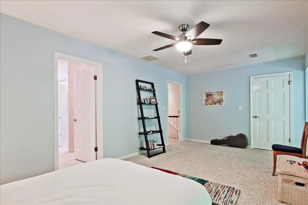 Carpeted bedroom featuring ceiling fan and connected bathroom