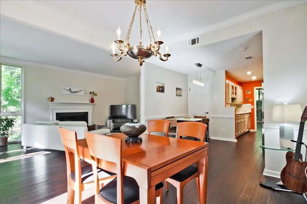 Dining area with crown molding, a chandelier, and dark wood-type flooring