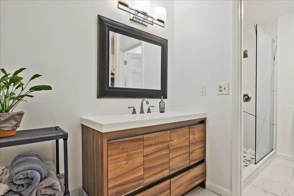Bathroom featuring tile floors, a shower with door, and vanity