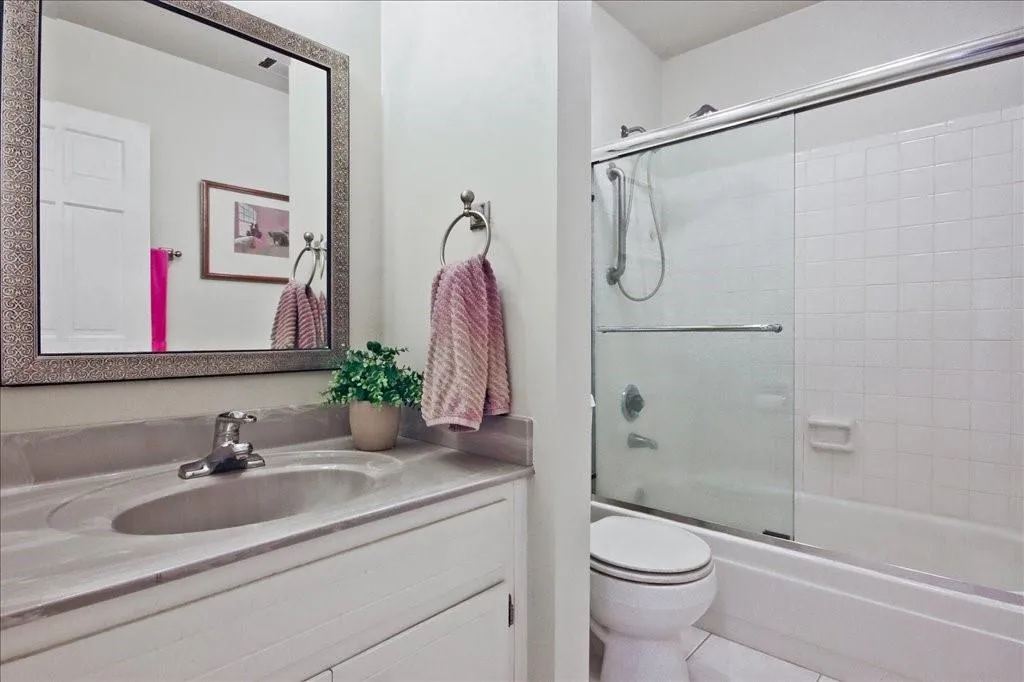 Full bathroom with tile flooring, combined bath / shower with glass door, vanity, and toilet