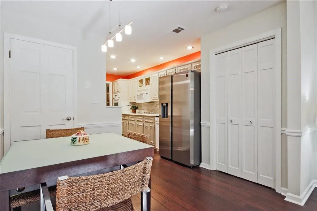 Kitchen with white cabinetry, hanging light fixtures, white appliances, dark hardwood / wood-style floors, and backsplash