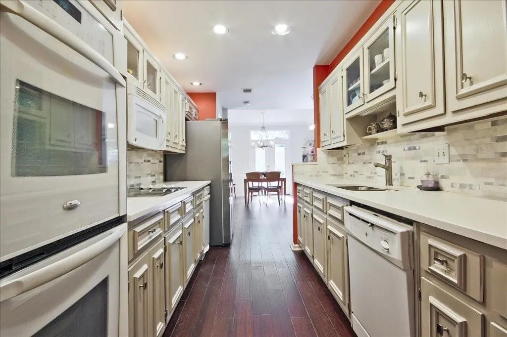 Kitchen with stainless steel appliances, sink, dark hardwood / wood-style flooring, and tasteful backsplash