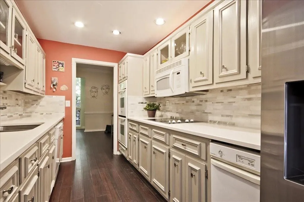 Kitchen with white cabinetry, white appliances, dark hardwood / wood-style floors, sink, and tasteful backsplash