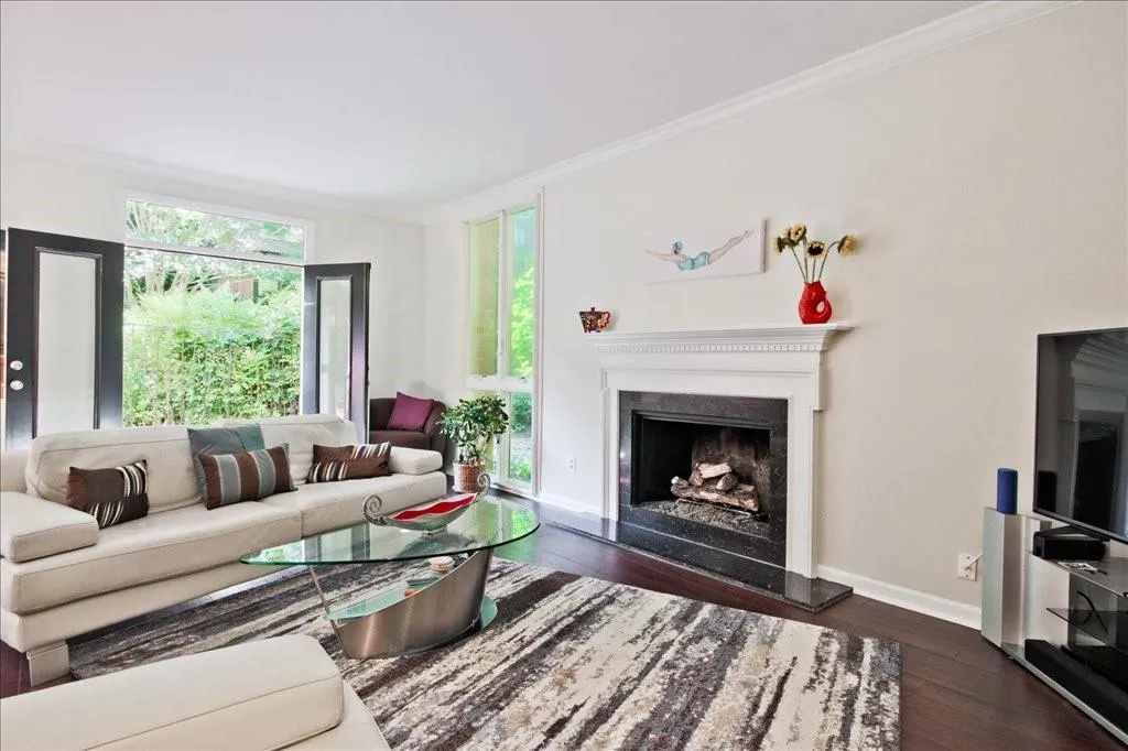 Living room with a high end fireplace, ornamental molding, and dark hardwood / wood-style flooring