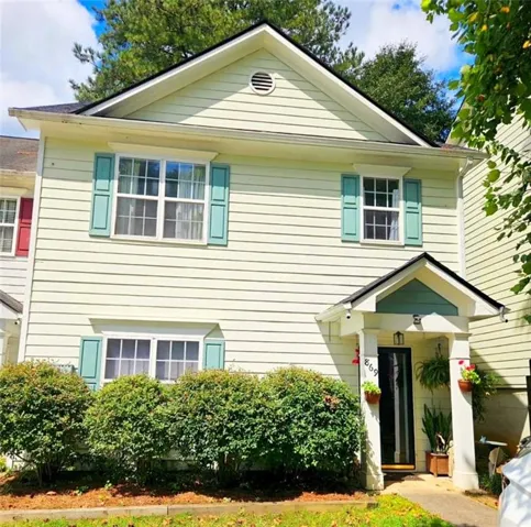 Two-story facade with horizontal siding, a covered entry, and green shutters