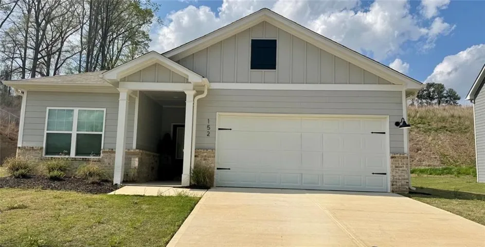 Light gray siding exterior with stone veneer accents, a covered front entry, and a two-car garage with decorative hardware