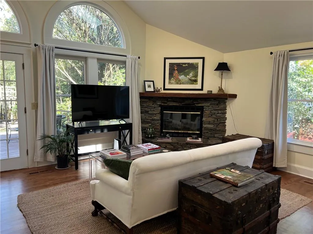 Living room featuring wood finished floors, a fireplace, and high vaulted ceiling