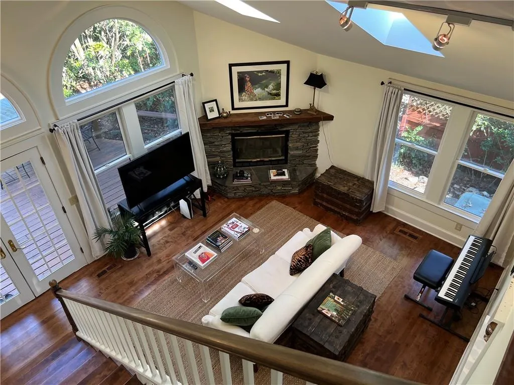 Living area with a skylight, wood finished floors, a fireplace, and vaulted ceiling