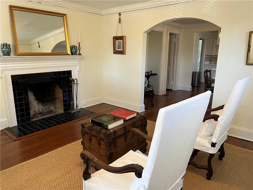 Living area with arched walkways, crown molding, wood finished floors, and a tiled fireplace