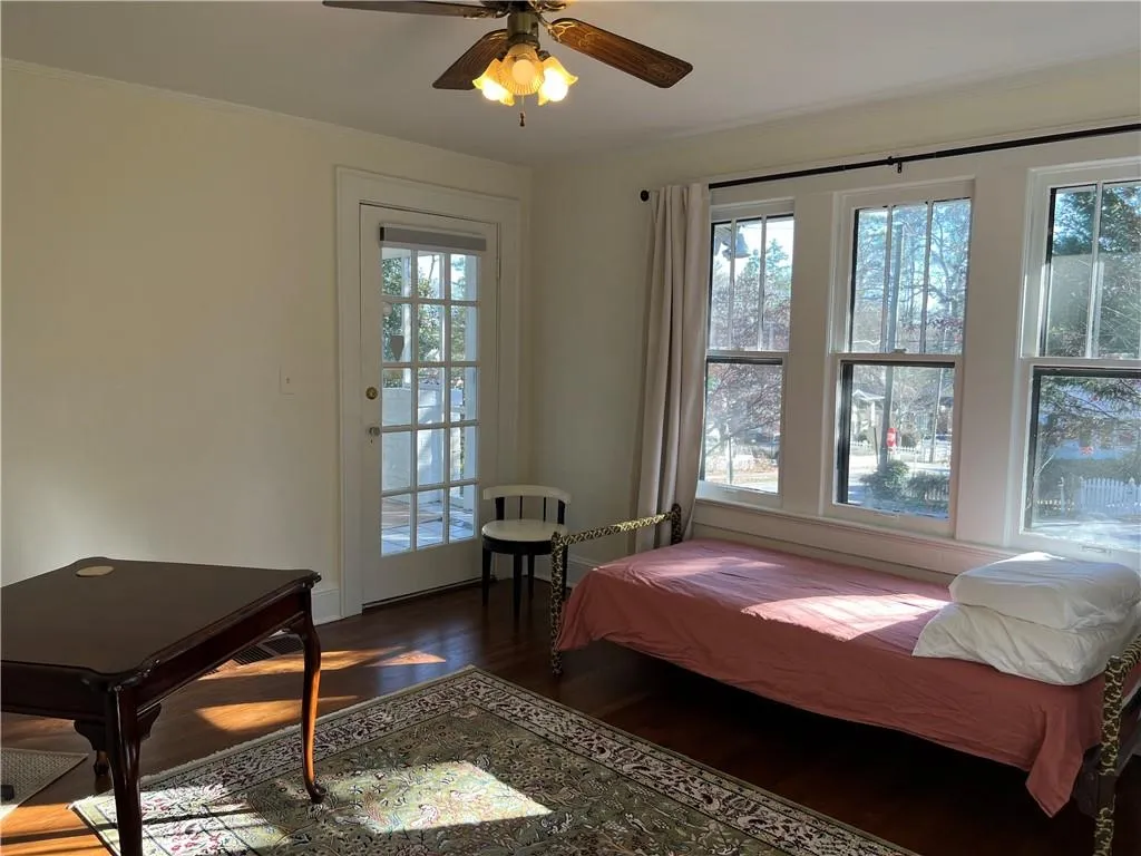 Bedroom featuring multiple windows, wood finished floors, ornamental molding, and ceiling fan