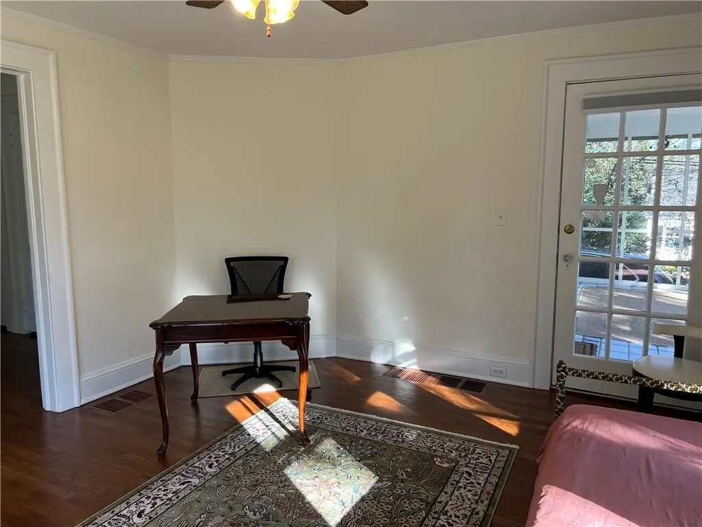 Home office featuring wood finished floors, ornamental molding, and a ceiling fan