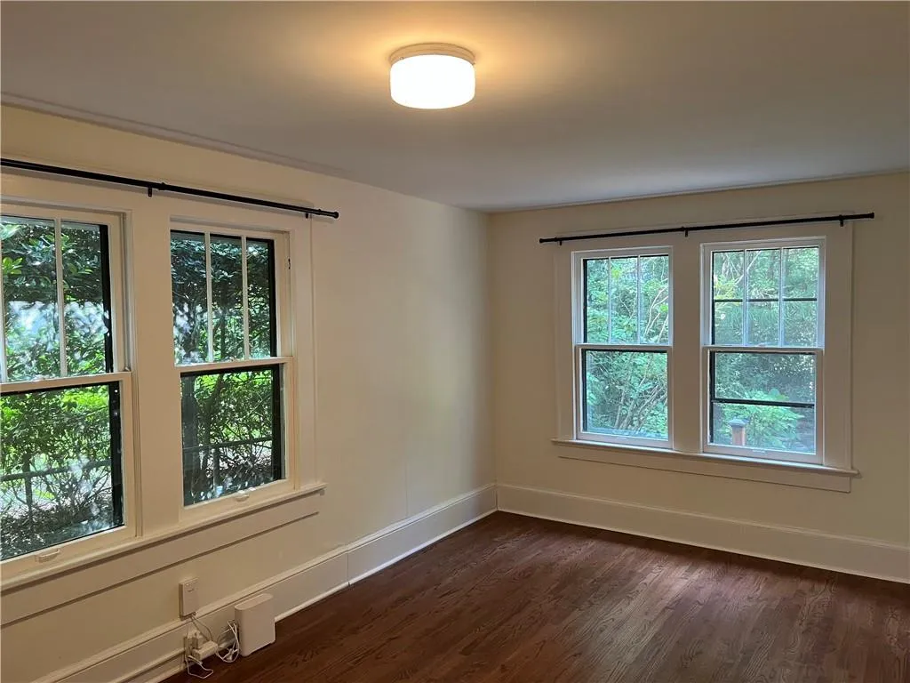 Spare room featuring dark wood-type flooring and baseboards