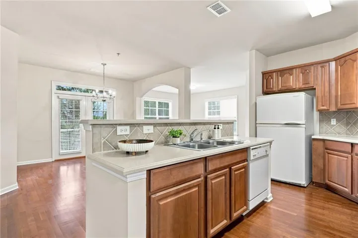 Kitchen featuring wood-finish flooring, light tone cabinetry, stone-finish countertops, and a tile backsplash