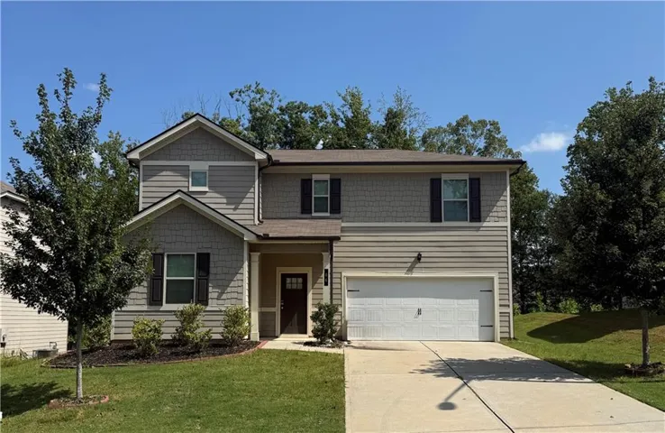 Two-story exterior with mixed siding, attached garage, covered entryway, and mature landscaping