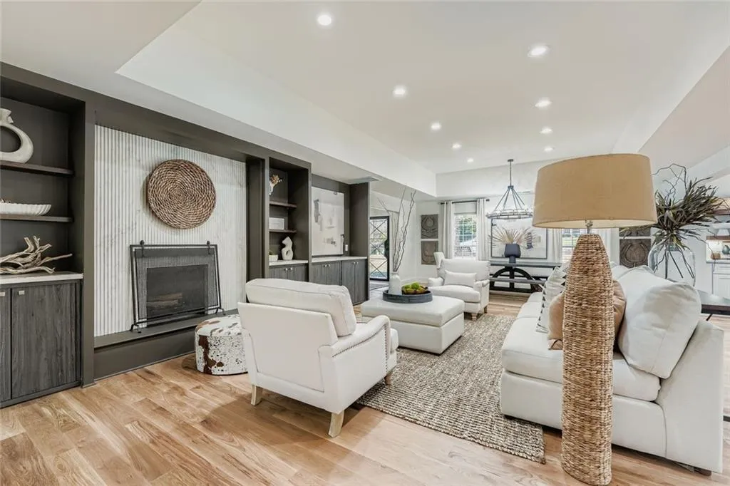 Living area featuring recessed lighting, a fireplace with raised hearth, built in features, and light wood-type flooring