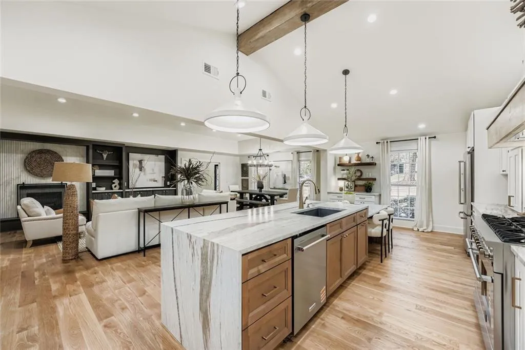 Kitchen with light stone countertops, open floor plan, stainless steel appliances, decorative light fixtures, and a fireplace