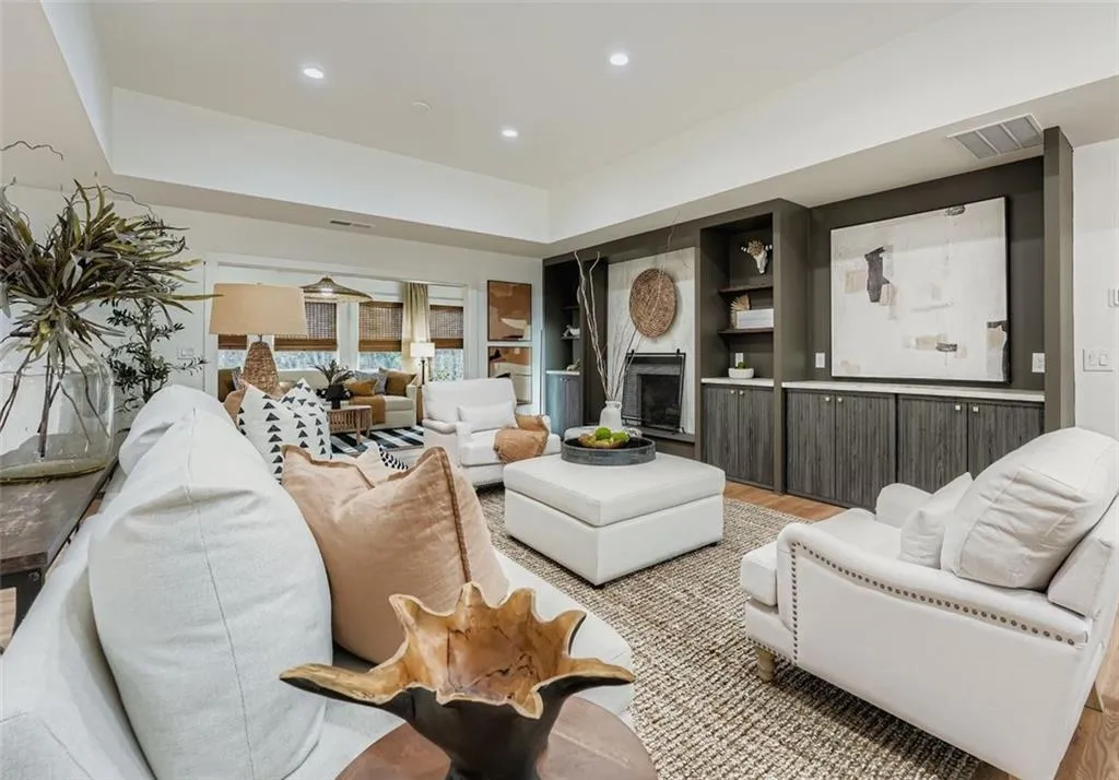 Living room featuring a fireplace, built in features, wood finished floors, recessed lighting, and a raised ceiling