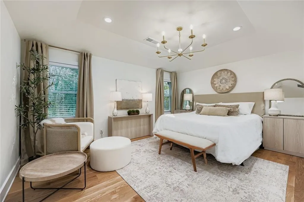Bedroom with light wood-type flooring, a chandelier, a tray ceiling, and recessed lighting