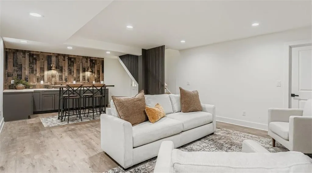 Living area featuring bar with sink, light wood-style flooring, and recessed lighting