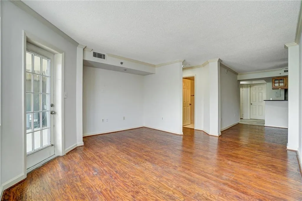 Unfurnished living room featuring crown molding, wood finished floors, and a textured ceiling