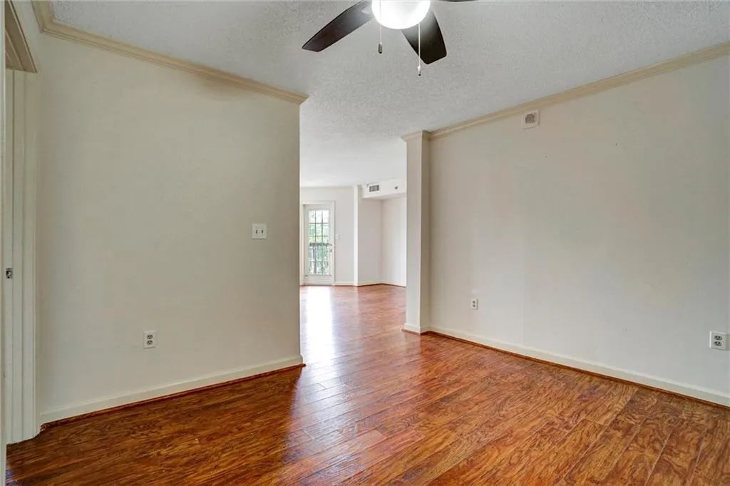Unfurnished room featuring a textured ceiling, ornamental molding, dark wood-type flooring, and a ceiling fan