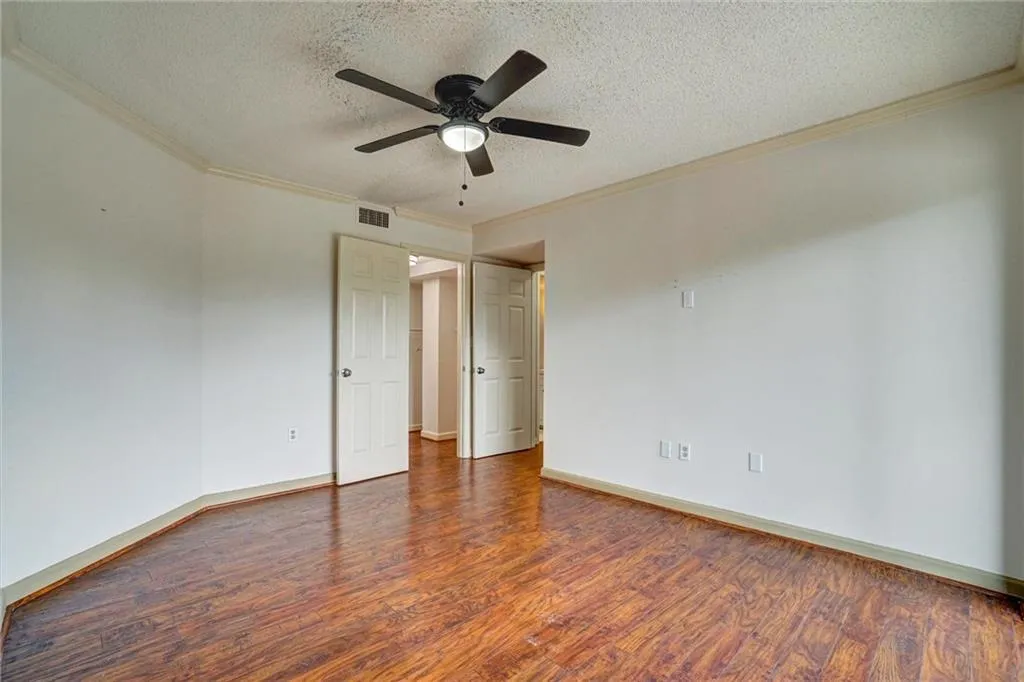 Spare room featuring a textured ceiling, ornamental molding, dark wood-style flooring, and ceiling fan