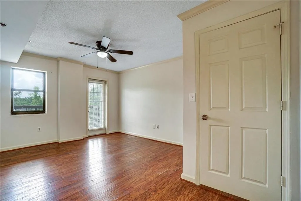 Unfurnished room featuring a textured ceiling, wood finished floors, crown molding, and a ceiling fan