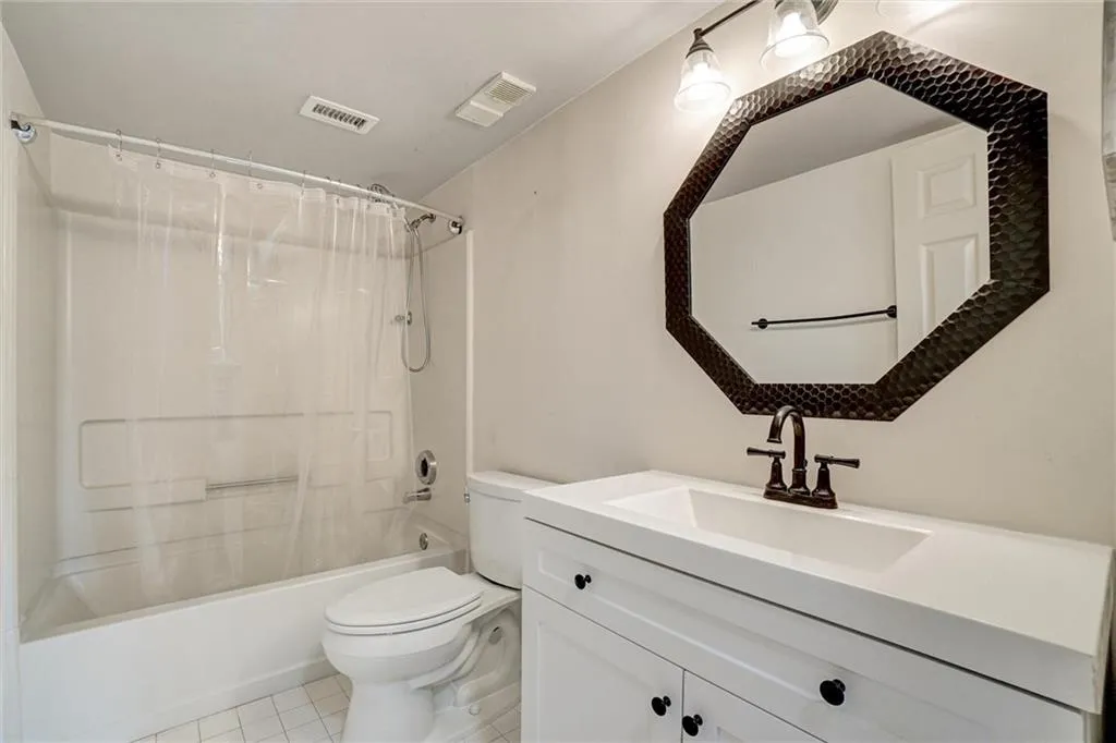 Bathroom with shower / bathtub combination with curtain, vanity, and light tile patterned flooring