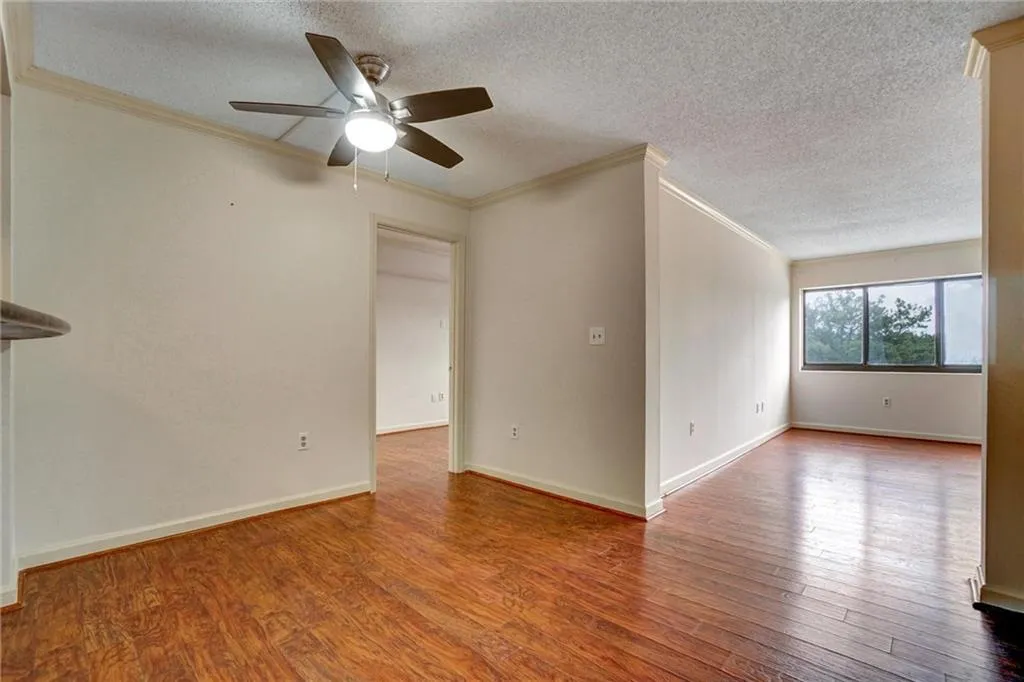 Unfurnished living room with crown molding, wood finished floors, a textured ceiling, and a ceiling fan