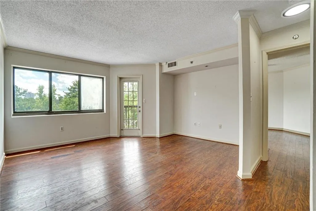 Unfurnished room with ornamental molding, dark wood-style floors, and a textured ceiling