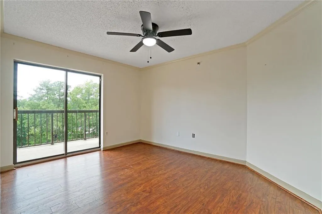 Empty room featuring a textured ceiling, wood finished floors, ornamental molding, and a ceiling fan