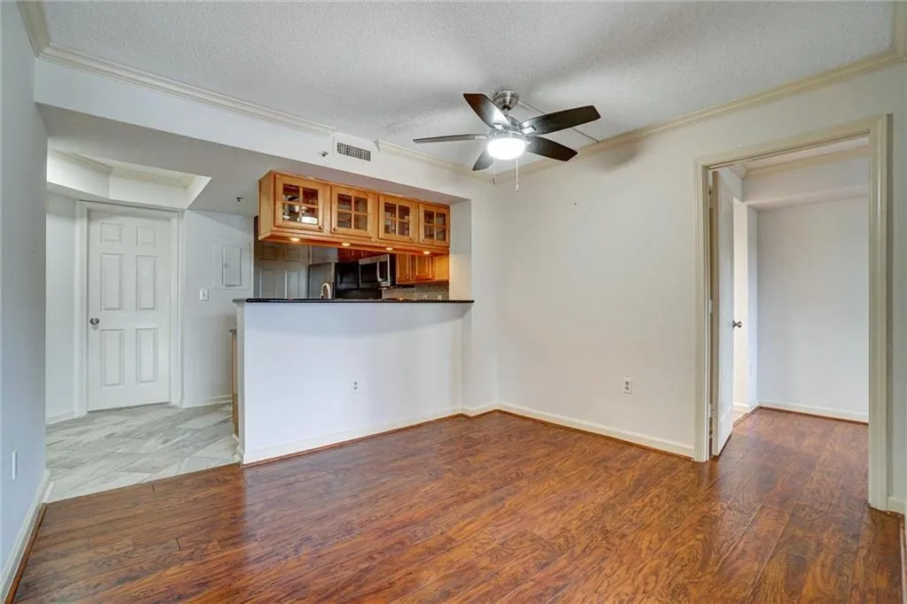 Unfurnished living room with crown molding, wood finished floors, a textured ceiling, and a ceiling fan
