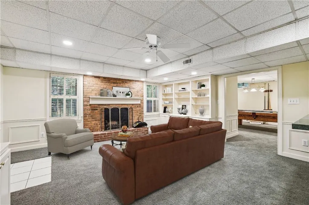 Lower level family room with built-ins and 1 of 3 fireplaces. Access to back yard as well as to the recreation room.  Virtually staged.