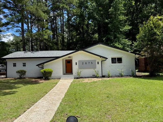 White brick exterior with a dark shingled roof and contrasting black trim
