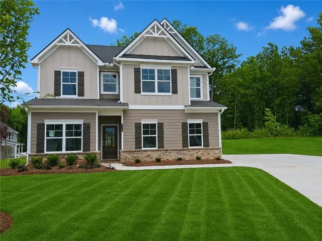 Craftsman-style home with board and batten siding, brick siding and a front yard