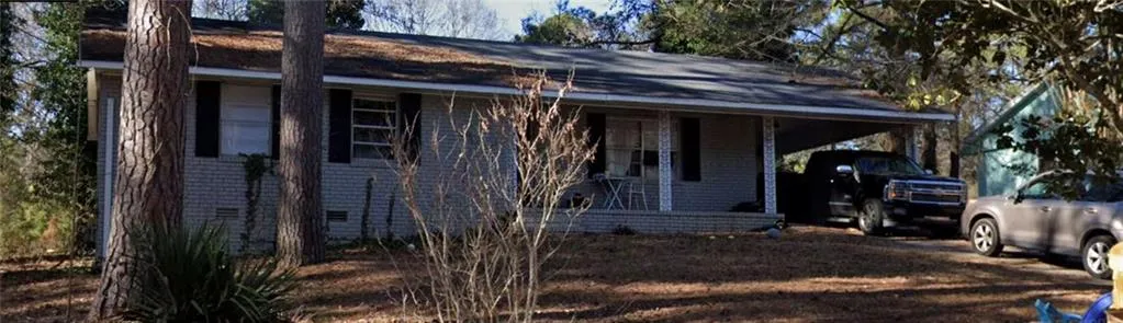 Brick exterior with a covered front porch and a carport