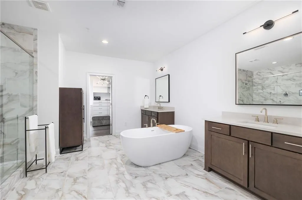 Luxurious spa like primary bath with oversized walk in shower, double vanities, custom backlit mirrors and walk in closet with custom shelving