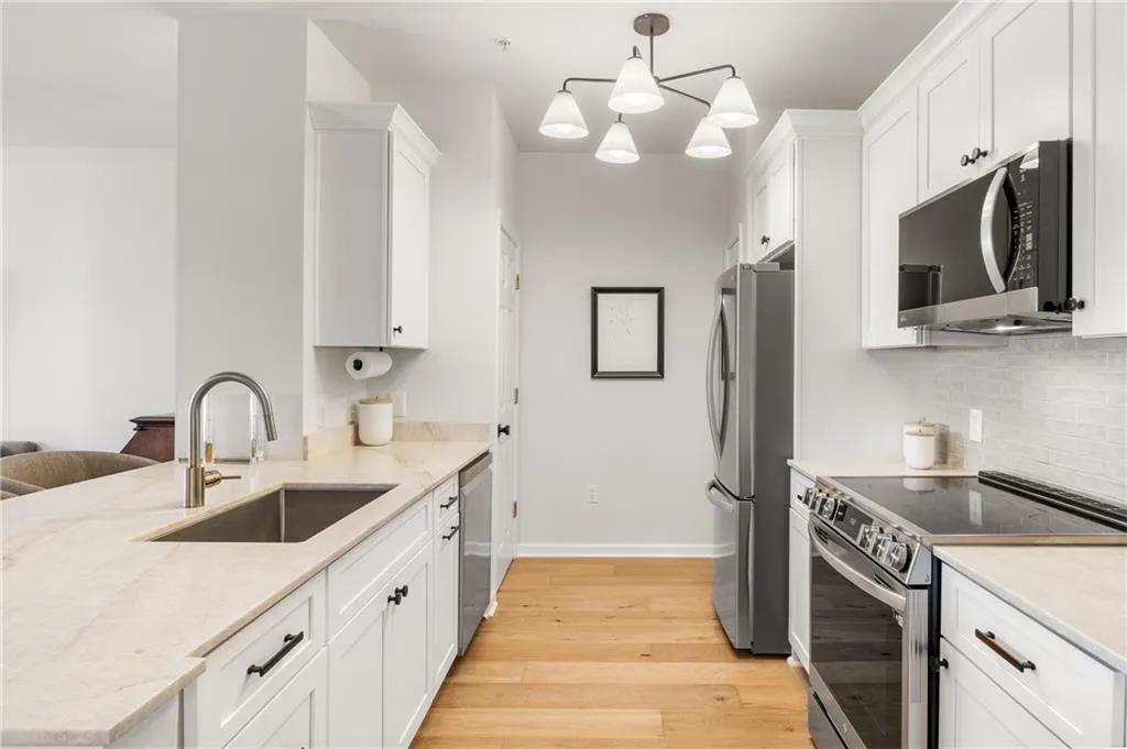 Kitchen with stainless steel appliances, light wood finished floors, white cabinetry, and a peninsula