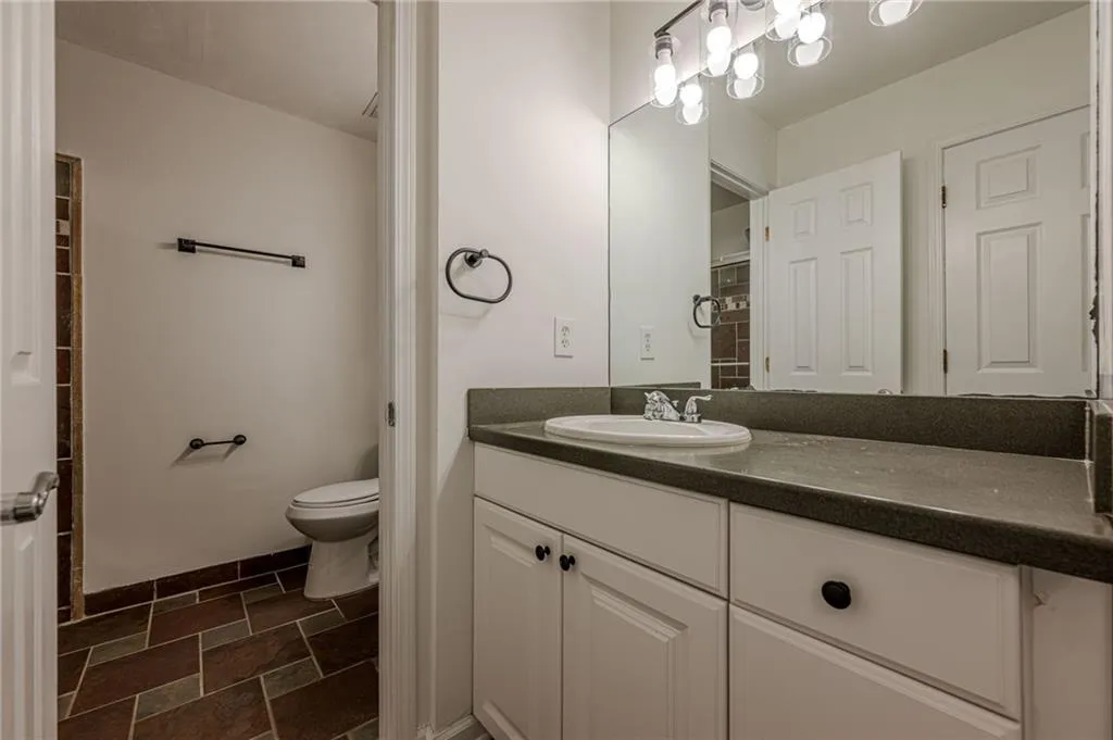 Full bath with vanity and dark stone finish floors