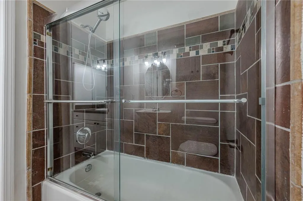 Full bathroom featuring combined bath / shower with glass door