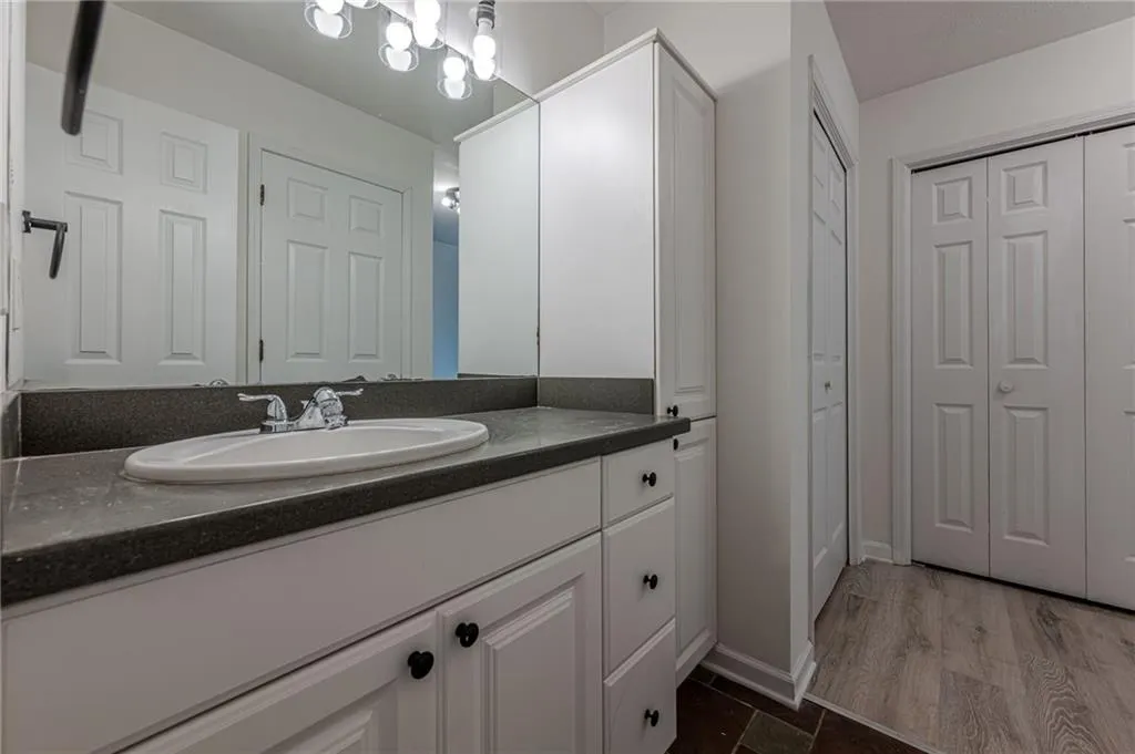 Bathroom with a closet, vanity, and dark wood-style floors