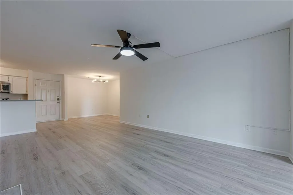 Unfurnished living room featuring light wood finished floors, a chandelier, and ceiling fan