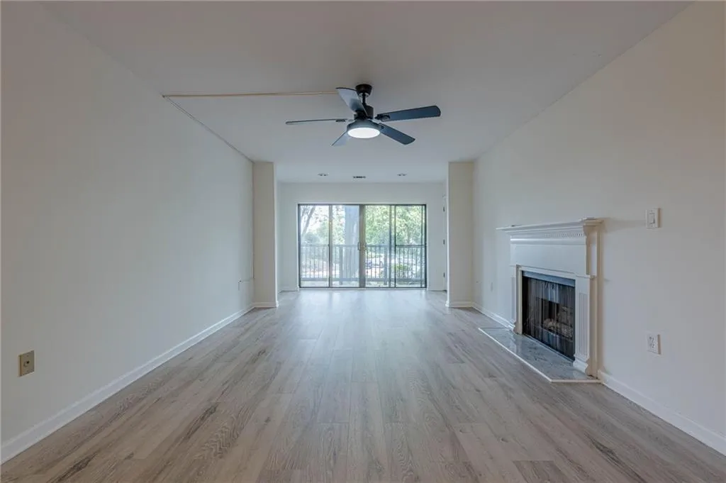 Unfurnished living room with light wood-style flooring, a fireplace with raised hearth, and ceiling fan