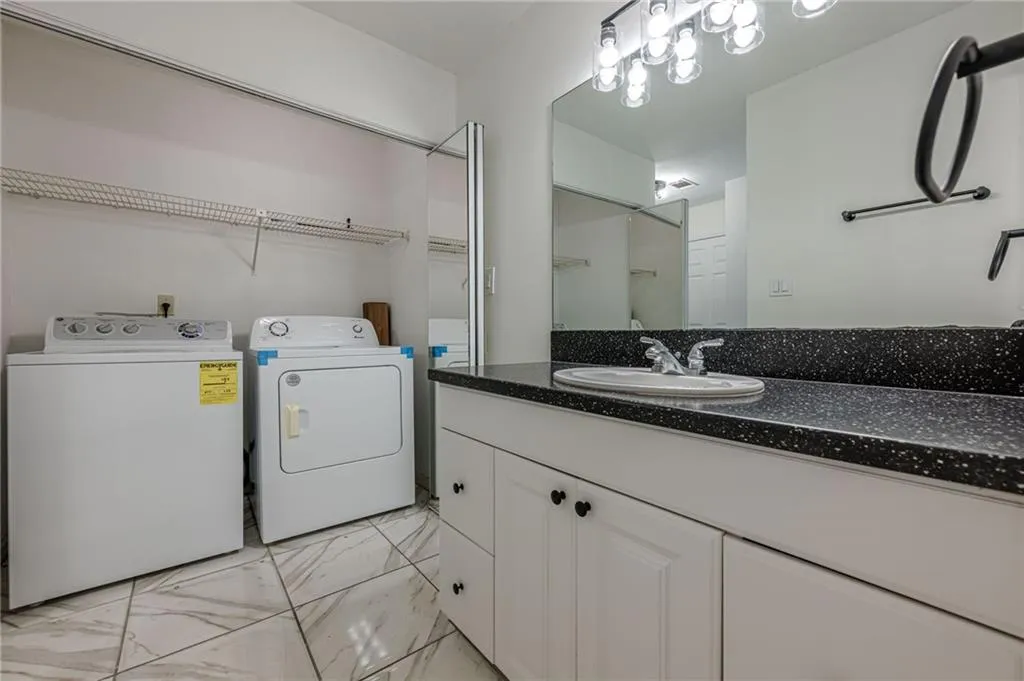 Bathroom featuring light marble finish floors, vanity, and washer and dryer